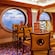 A lounge with tall bar tables and high back stools has large porthole windows